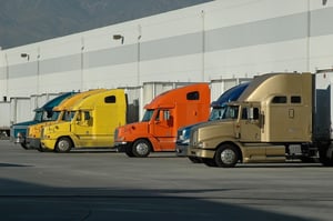 Trucks & trailers stationary at loading bays on side of warehouse