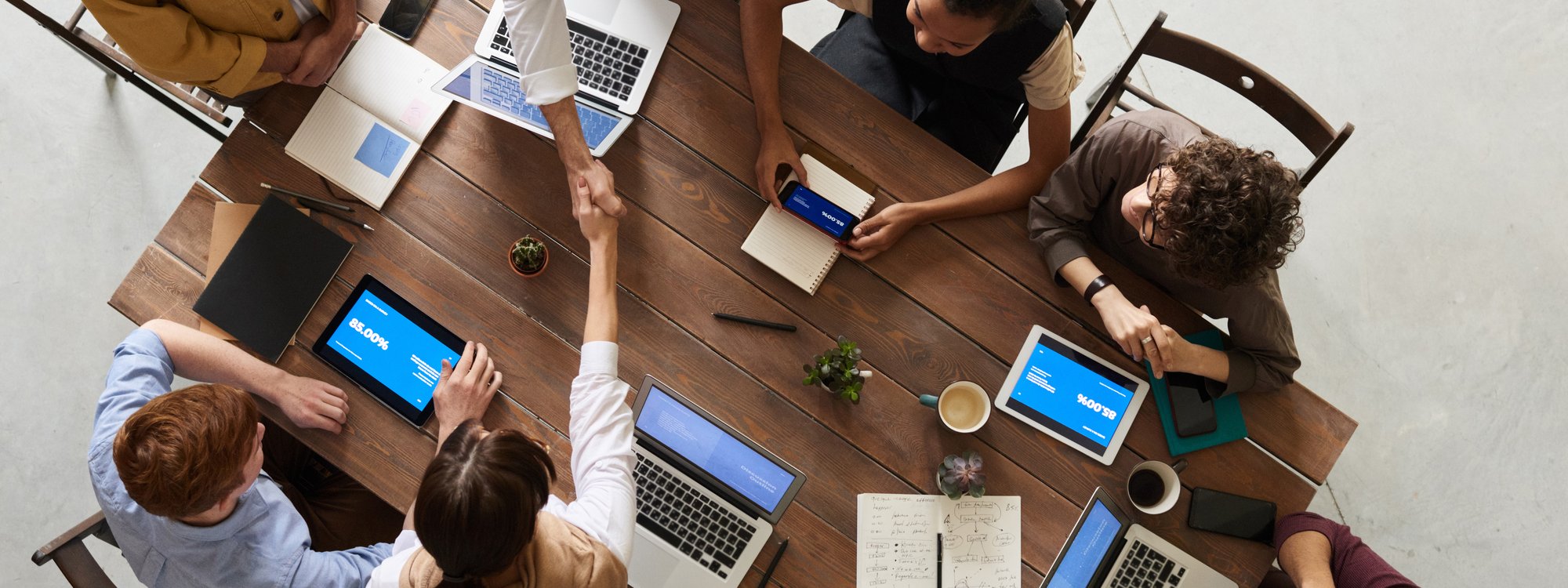 Group photo of business team members shaking hands while seated at table