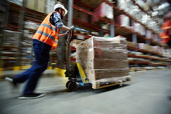 Warehouse worker moving a pallet of materials, utilizing spare parts inventory management best practices
