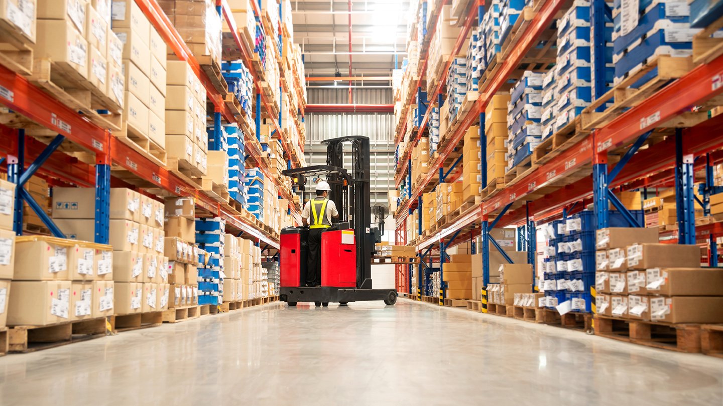 Warehouse worker in forklift placing pallet of goods safely, having considered clear stack height